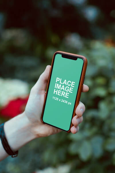 Holding an iPhone X outdoors