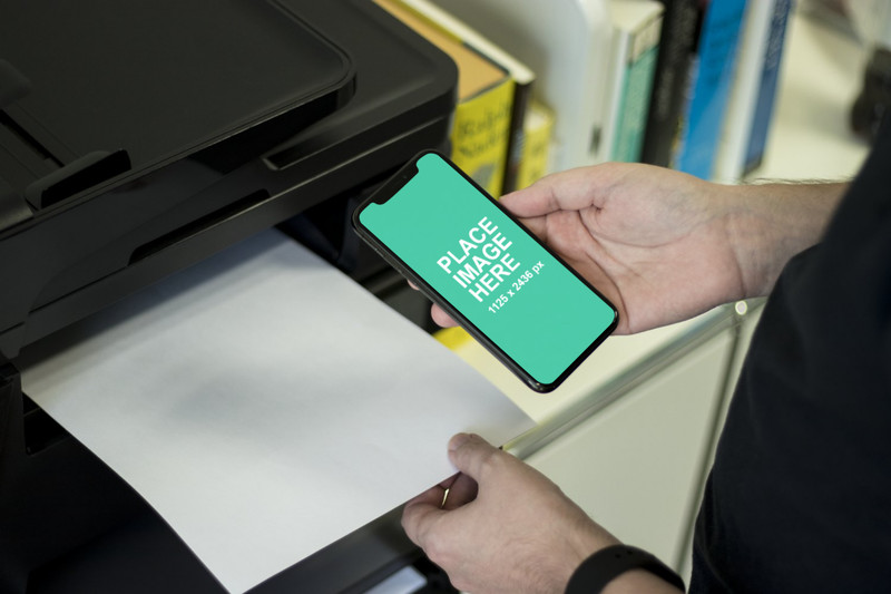 Man holding iPhone X at printer