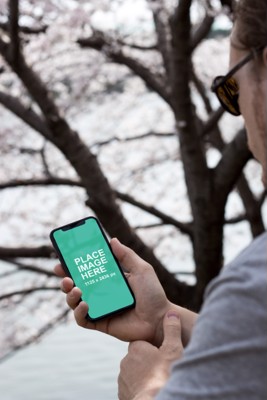 Man holding iPhone X in forest