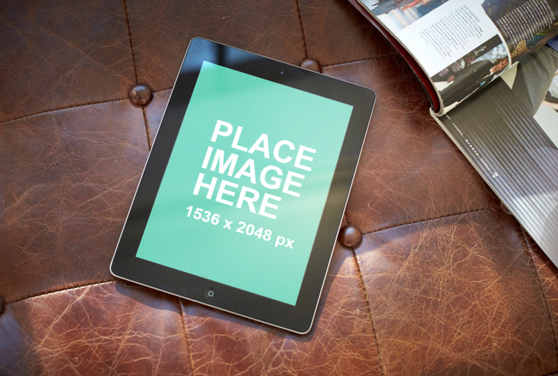 Black iPad on brown leather sofa