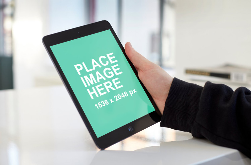 iPad mini in hand on white table landscape