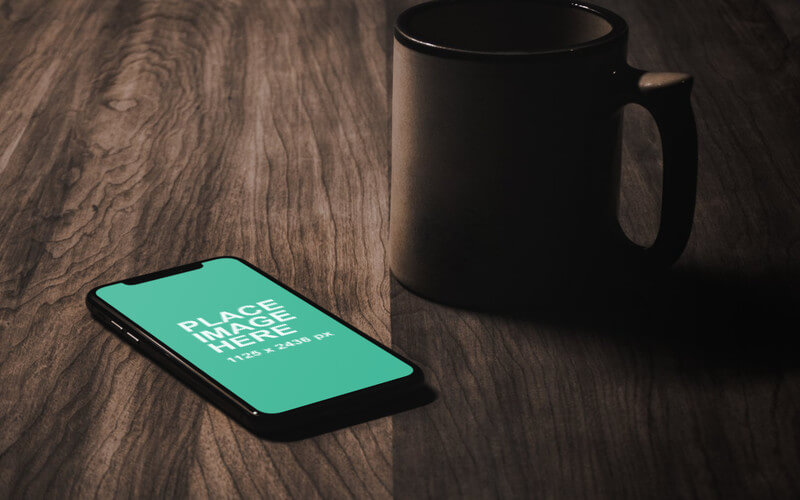 iPhone X and mug on table