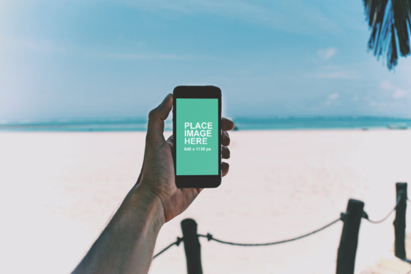 Man holding iPhone at beach