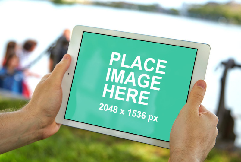 Man holding white iPad air in a park