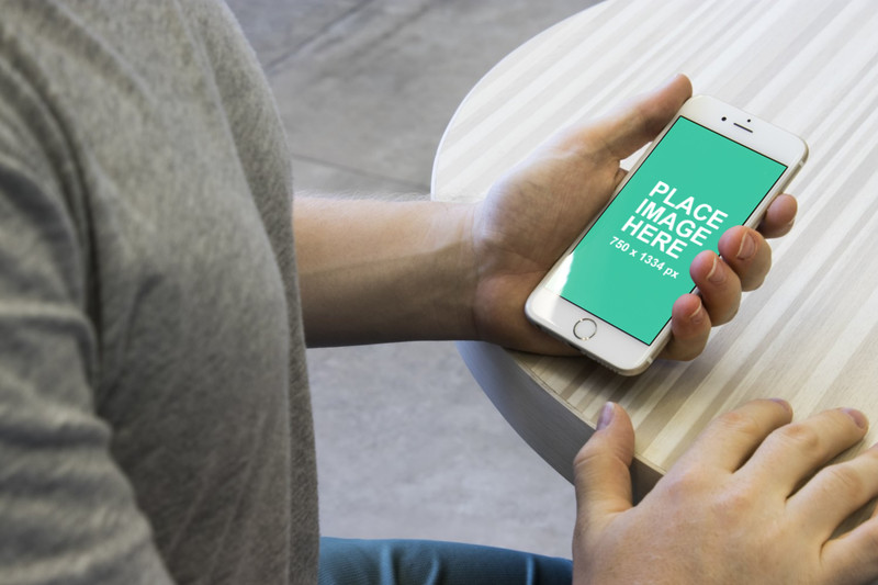 Man holding white iPhone 6 on table
