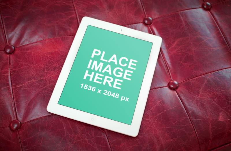 White iPad on red sofa